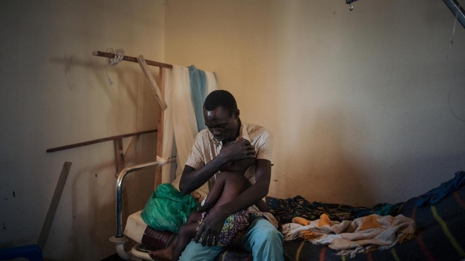 Un père tient sa fille de deux ans souffrant de la rougeole
