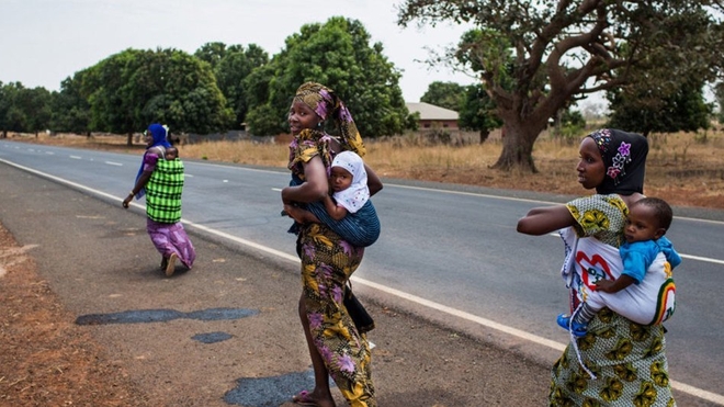 Des femmes rentrent chez elles après avoir fait vacciner leurs enfants sur le site de proximité d'un centre de santé en Gambie