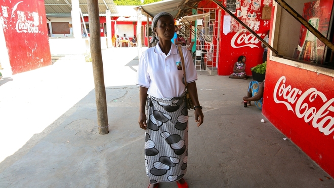 Au Mozambique, une femme entourée de panneaux d'affichage Coca-Cola.